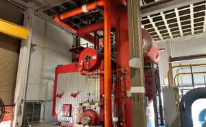 Industrial boiler system inside a facility with red and orange piping at the OU Health Sciences Center.